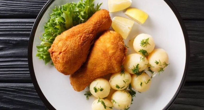 Ein Teller Backhendl, ein paniertes und gebratenes Hühnergericht, serviert mit Kartoffelsalat.
