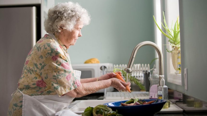 Eine Oma in der Küche unterrichtet ihr Enkelkind